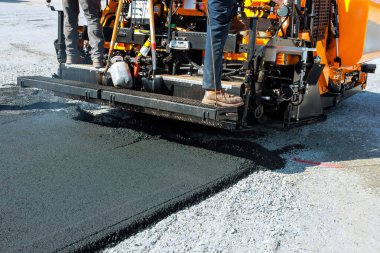 İnşaat işçileri şehir yolunda asfalt kaldırım döşemek için asfalt kaldırım kullanıyor.