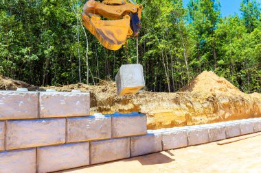 Ağır makineler beton bloğu duvarın altına yerleştirip istinat duvarı oluşturur