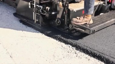 Ağır makineler yol onarımı için yol yüzeyine sıcak asfalt uygular