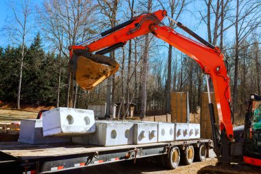 Bir kazıcı inşaat alanındaki kamyondan büyük beton blokları taşır