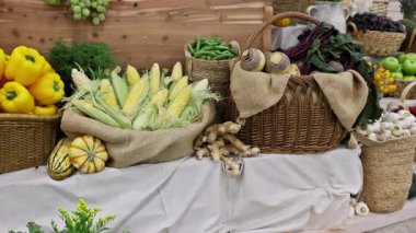 Parlak portakallar, canlı pazar ortamında çeşitli meyve sebzeleri arasında sepetten sarkan.