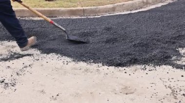 İşçiler yol altında kürek kullanırken yolda asfalt düzleştiriyorlar