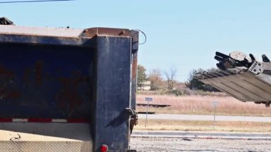 Skid dümen yükleyicisi inşaat alanındaki toprak yığınından çöp kamyonuna boşaltıyor.