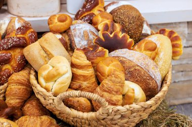 Yerel pastanede davetkar bir şekilde düzenlenmiş farklı pişmiş ekmeklerle dolu dokuma sepet.