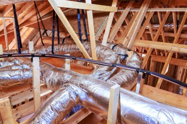 İşçiler yenileme işlemi sırasında çatı katındaki ahşap kirişlere metal boru döşüyorlar.