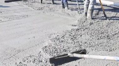İnşaat işçileri yoğun çalışma sahasında beton yüzeyi araçlarla düzleştirmeye hazırlanıyorlar..