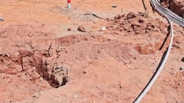 Kazı çalışmaları, kurumuş topraktaki derin siperleri ortaya çıkardı. Atık su borularının kurulumuna işaret eden borular döşendi.