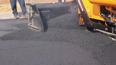 İşçi, yol çalışmaları sırasında yerleşim yerlerindeki çukurları asfaltla doldurmak için kürek kullanıyor.