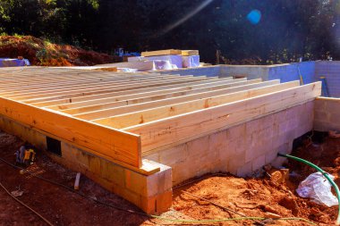 Workers are constructing new building with wooden beams on cinder block foundation