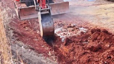 Kazıcı kazıcı çukur kazmak için toprak, toprak kazmak için yer yakınındaki kayaları temizler.