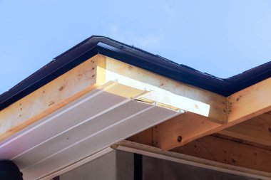 İşçiler, ev yenileme projesi sırasında çatının kenarına vinil PVC kaplama monte ediyorlar