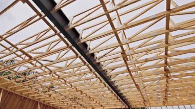 İşçiler ahşap kirişleri kullanarak çatı iskeleti inşa ediyorlar. İnşaat alanında metal desteklere katılıyorlar.