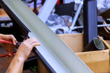 Müteahhit, çalışma alanında çeşitli malzemelerle çevriliyken metal kanalları kesmek için araçlar kullanır..