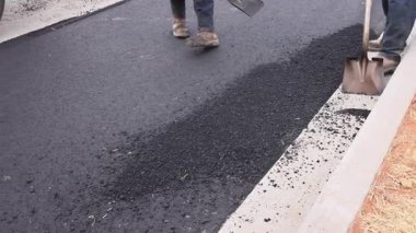 İşçiler yol çalışmaları sırasında pürüzsüz sürüş yolu yüzeyi oluşturmak için asfalt kullanırlar