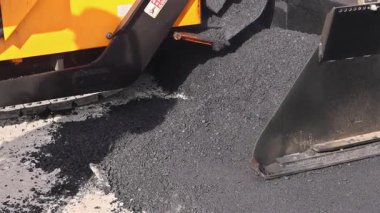 İşçi, yeni asfalt döşeyen asfalt kaldırım makinesini çalıştırıyor.