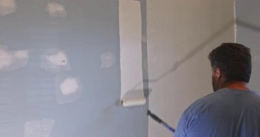 Becerikli adam duvarları silindir duvarla boyuyor. Evin yenilenmesi için yeni boya katmanları var..