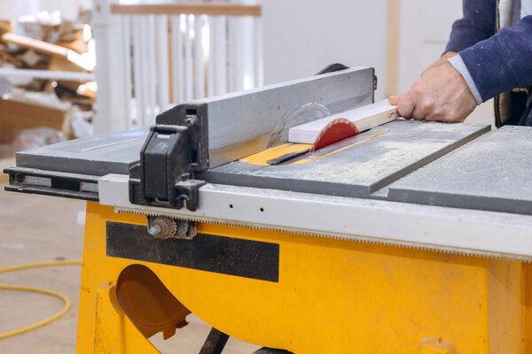 Carpenter operates table saw in construction area saw cuts through piece of wood.