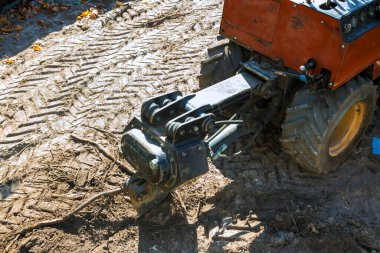 Makine inşaat alanındaki toprağı kazıyor. Cihazların etrafındaki kuru yapraklar..