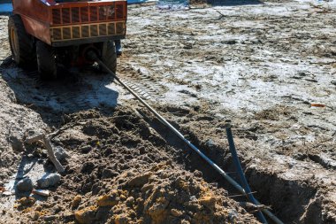 İşçiler inşaat alanındaki siperlerden kablo çekmek için makine kullanıyorlar.