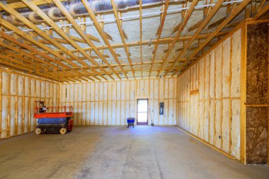 İnşaat halindeki büyük odanın duvarlarında yalıtım malzemesi, giriş kapısının içine yerleştirilmiş aletler var.