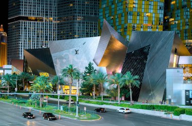 8 Şubat 2026 Las Vegas NV ABD halkı Las Vegas 'taki LV mağazasının önünden gece geçmekte, büyük binalar çevreleyen.