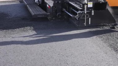 Paving makinesi, araçlar için daha pürüzsüz sürüş yüzeyi oluşturmak için yola asfalt yayar.