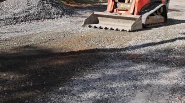 İnşaat aracı, inşaat alanındaki yol yüzeyindeki çakılları pürüzsüz kılmak için bıçak kullanıyor.