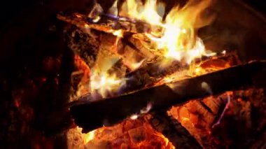 Kamp ateşinde yanan odunlardan yükselen parlak alevler gece boyunca ısınan ateşler çevreyi aydınlatır..