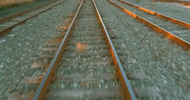 Şehir batımında tren rayları paralel ilerliyor. Taşlarla kaplı, raylar arasında küçük bitkiler yetişiyor..