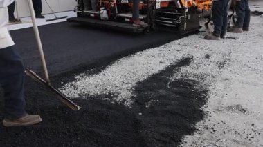 10 Aralık 2025 Chicago IL US. İşçiler, ağır ekipman el aletleriyle yol yüzeyine sıcak asfalt yerleştiriyorlar.