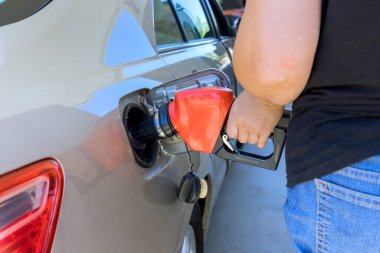 Yakıt ikmali sırasında benzin istasyonunda servis işçisi arabalarını benzinle dolduruyor..