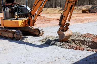 İşçi inşaat alanında hendek kazmak için bir kazıcı çalıştırıyor
