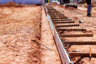 İşçiler, kırsal bölgedeki inşaat sahasına ahşap formlarla beton temeller atmaya hazırlanıyorlar..