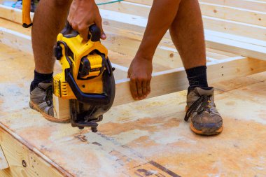 İşçi inşaat alanında ahşap çerçeveleri emniyete alırken el testeresi tutuyor.