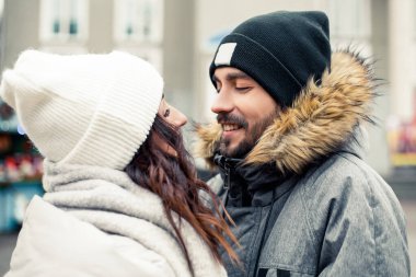 Genç ve güzel bir çift gelin damat yeni evliler sokak ortasında öpüşüyor, sarılıyor, birlikte vakit geçiriyor, mutlu bir şekilde gülümsüyor. Yeni yıl Noel süsleri, Sevgililer Günü konsepti.