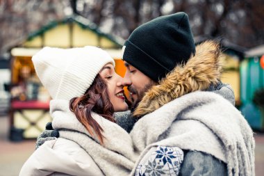 Genç ve güzel bir çift gelin damat yeni evliler sokak ortasında öpüşüyor, sarılıyor, birlikte vakit geçiriyor, mutlu bir şekilde gülümsüyor. Yeni yıl Noel süsleri, Sevgililer Günü konsepti.