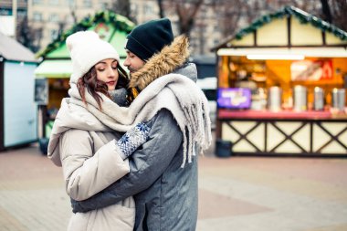Genç ve güzel bir çift gelin damat yeni evliler sokak ortasında öpüşüyor, sarılıyor, birlikte vakit geçiriyor, mutlu bir şekilde gülümsüyor. Yeni yıl Noel süsleri, Sevgililer Günü konsepti.