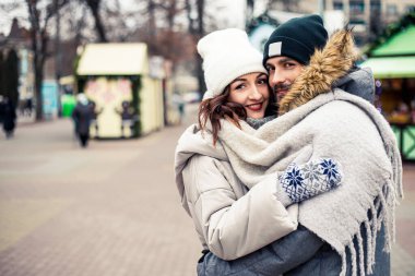 Genç ve güzel bir çift gelin damat yeni evliler sokak ortasında öpüşüyor, sarılıyor, birlikte vakit geçiriyor, mutlu bir şekilde gülümsüyor. Yeni yıl Noel süsleri, Sevgililer Günü konsepti.