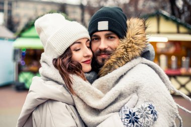 Genç ve güzel bir çift gelin damat yeni evliler sokak ortasında öpüşüyor, sarılıyor, birlikte vakit geçiriyor, mutlu bir şekilde gülümsüyor. Yeni yıl Noel süsleri, Sevgililer Günü konsepti.