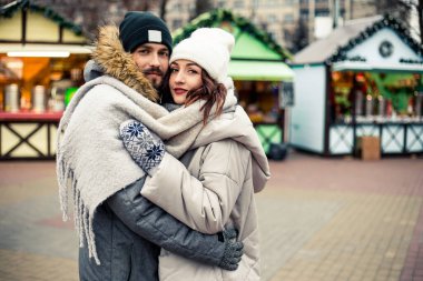 Genç ve güzel bir çift gelin damat yeni evliler sokak ortasında öpüşüyor, sarılıyor, birlikte vakit geçiriyor, mutlu bir şekilde gülümsüyor. Yeni yıl Noel süsleri, Sevgililer Günü konsepti.