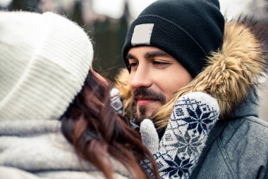 Genç ve güzel bir çift gelin damat yeni evliler sokak ortasında öpüşüyor, sarılıyor, birlikte vakit geçiriyor, mutlu bir şekilde gülümsüyor. Yeni yıl Noel süsleri, Sevgililer Günü konsepti.