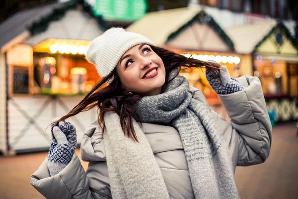 Young pretty smiling white teeth woman face looking at the camera, warm mittens with a pattern. Cold weather, winter holidays, travel. New Year Christmas decorations, Valentines Day concept.