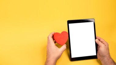 Siyah tablet beyaz tablet beyaz ekran izole edilmiş sarı parlak arkaplan. Kırmızı kalp şekli 14 Şubat, Sevgililer Günü konsepti. Romantik 