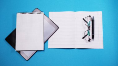 Düz tablet beyaz not defteri mavi arkaplanı izole etti. Dijital modern alet, uzaktan kumandalı çalışma konsepti. Yüz yolculuğu cerrahi tek kullanımlık maske. Ev konseptinde çalış.