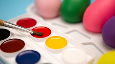 Mavi arka planda dağınık renkli yumurtalarla süslenmiş düz bir el boyası seti. Bahar tatiline hazırlanıyorum. Mutlu Paskalya kompozisyonu. Boş alanı kopyalayan resim