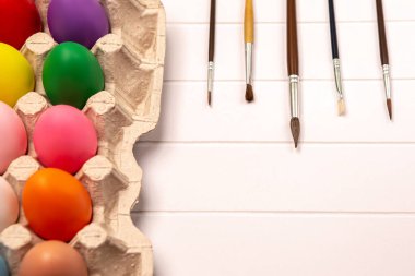 Renkli el boyalı tavuk yumurtaları karton kağıt paketler. Mutlu Paskalya kompozisyonu. Bahar tatiline hazırlanıyorum. Boyalı ve fırçalı palet.