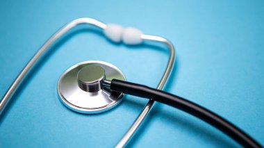 Siyah modern steteskopu mavi arka planda yansıması olan fotokopi alanı ile kapatın. Tek kullanımlık maske. Tıbbi hemşire ya da doktor ekipmanı objesi. Tıp sağlık hizmetleri kavramı.