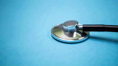 Siyah modern steteskopu mavi arka planda yansıması olan fotokopi alanı ile kapatın. Tek kullanımlık maske. Tıbbi hemşire ya da doktor ekipmanı objesi. Tıp sağlık hizmetleri kavramı.