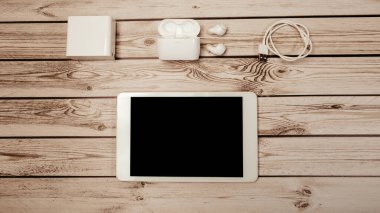 En üstteki düz görünüm, elektrik tedarik ünitesinin kablosuz bluetooth kulaklık kablosu ve ahşap masa masasındaki beyaz dijital modern tablet bilgisayarın görüntüsüydü. Evde çalış, keyfine bak. Model