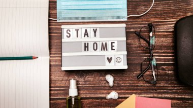 Mavi maske masalı küçük şişe el dezenfektanı, koronavirüs önleyici. Klavye ve fare gözlükleri. Ev konseptinde yazıt çalışması, kalem kablosuz kulaklık.